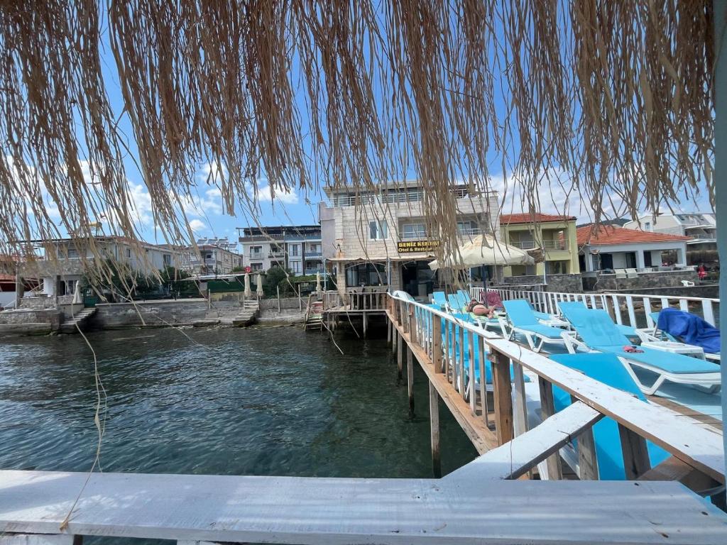 a dock with blue lounge chairs on the water at Deniz Kenarı Beach & Garden in Ayvacık
