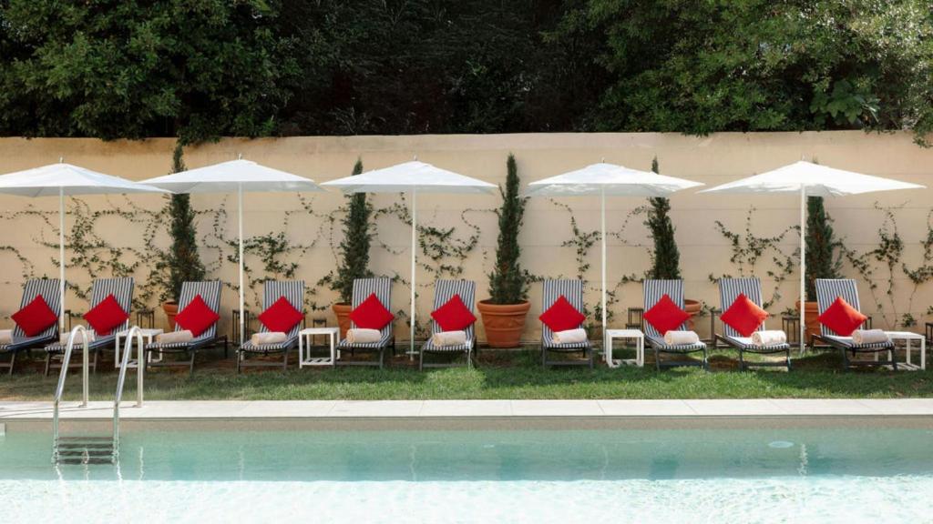 a group of chairs and umbrellas next to a pool at Hotel Indigo Florence by IHG in Florence