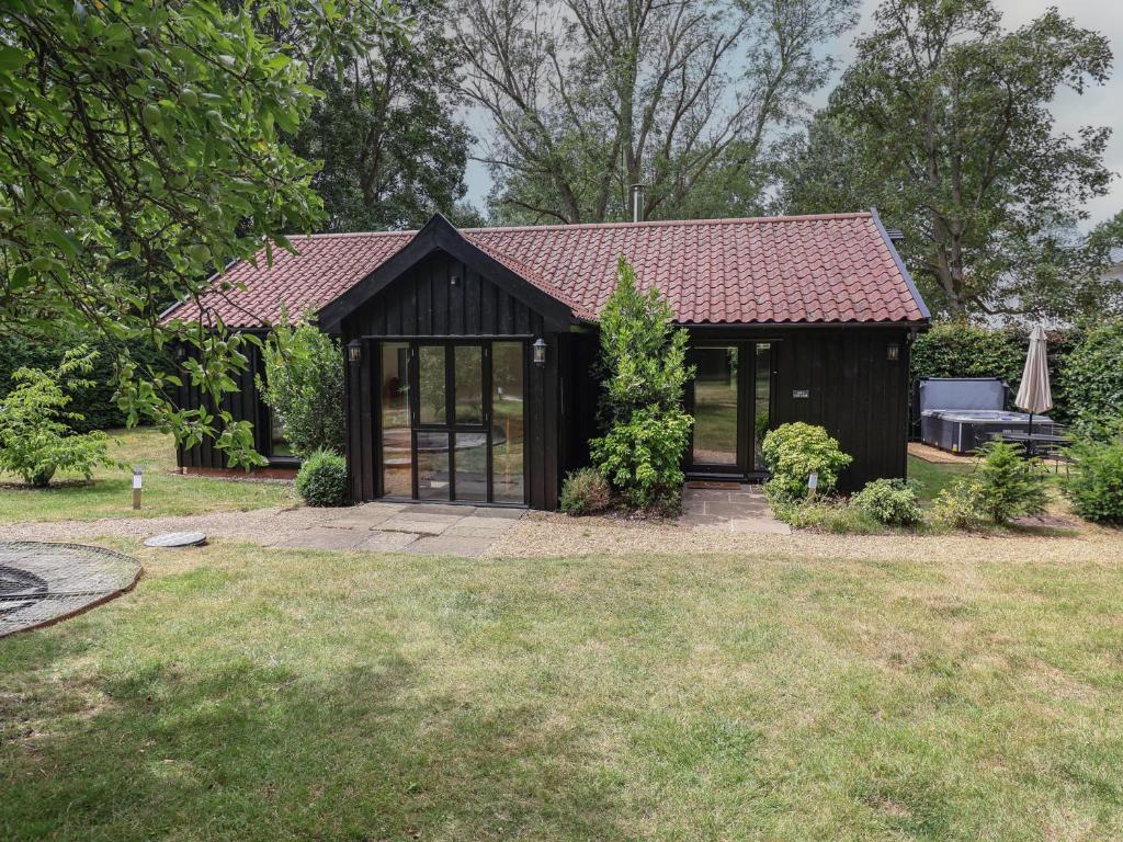 a small house with a roof in a yard at Owl Cottage in Woodbridge