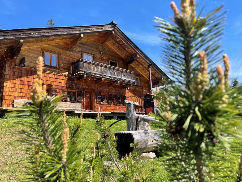 a log cabin on a hill with trees in the foreground at Herbst Alm in Unken