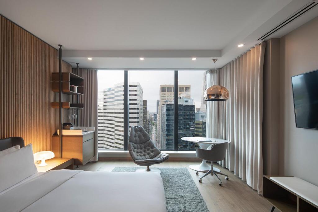 a hotel room with a bed and a large window at Hôtel Le Germain Montréal in Montreal