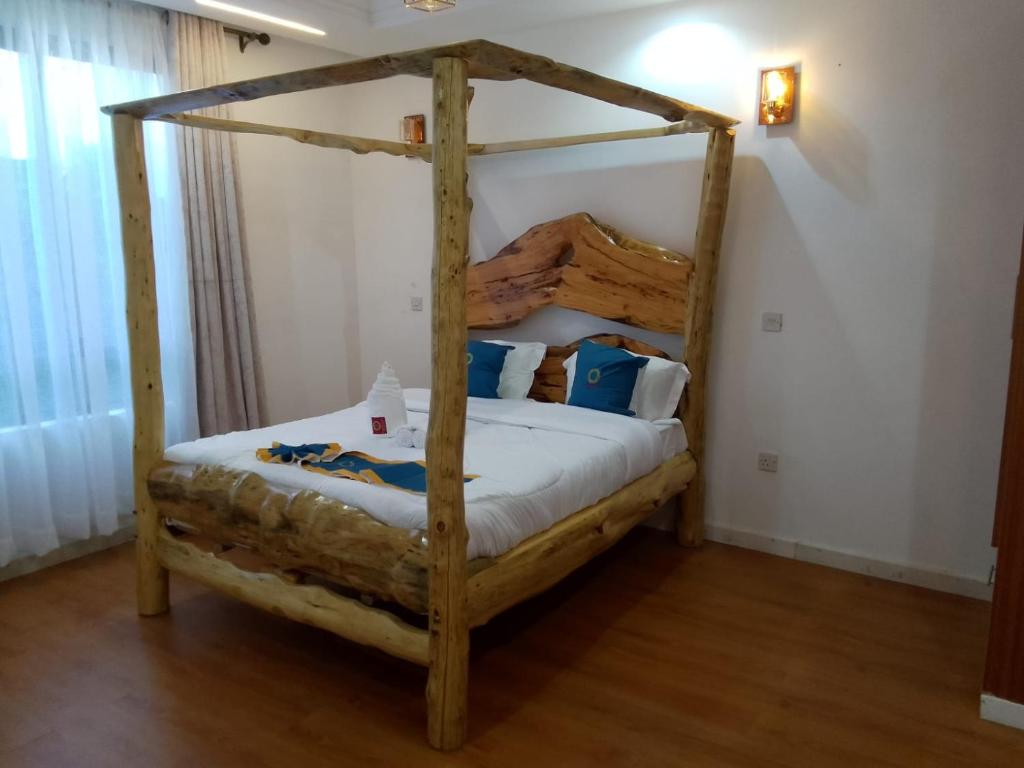 a bedroom with a four poster bed in a room at Goldenview Gardens Elementaita in Gilgil