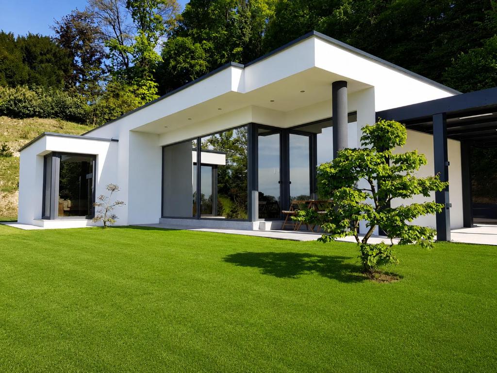 a white house with a green lawn at Apartma Belvi in Brežice