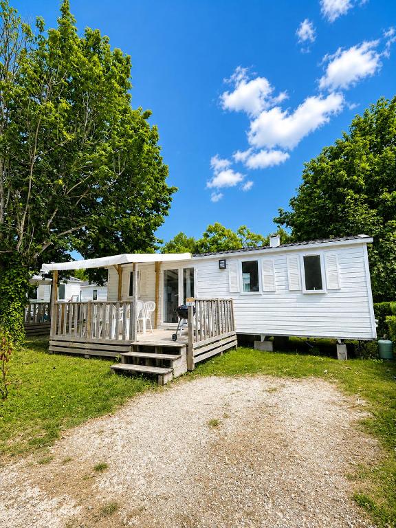 a mobile home with a porch and trees at Mobile-home in Ivry-la-Bataille