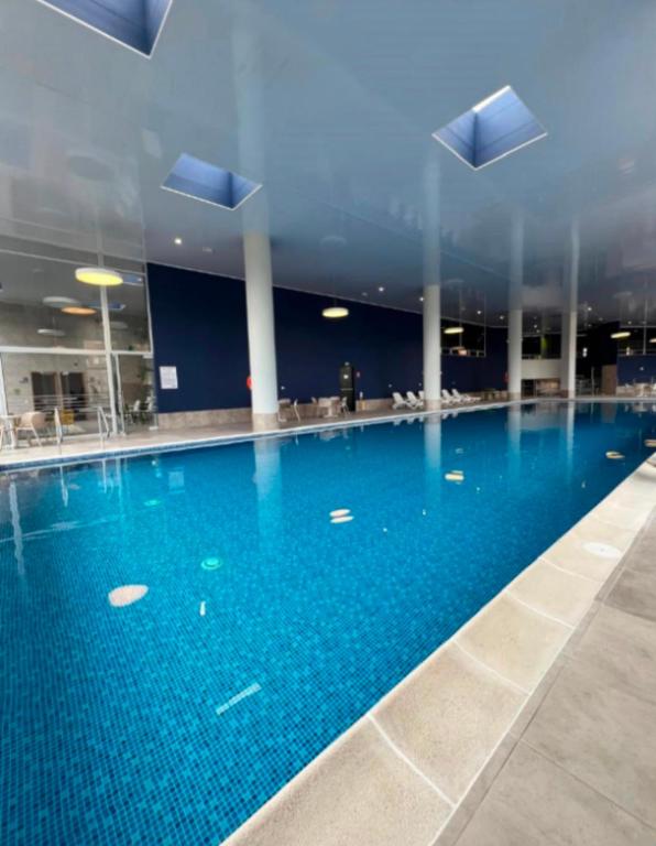 a large swimming pool with blue water in a building at Fly At Home Bogotá in Bogotá