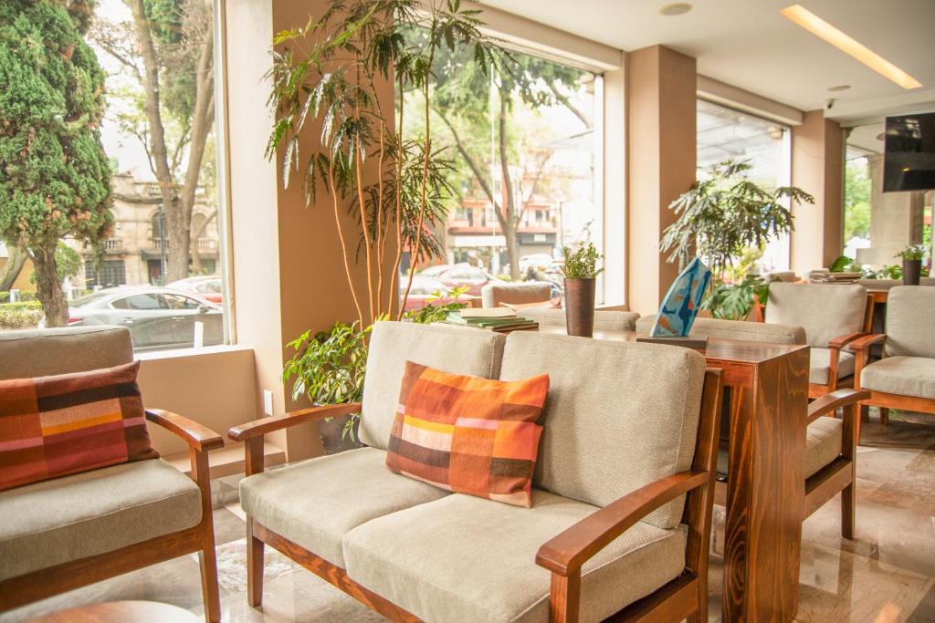 A window-lined hotel lounge with sofa seating and indoor plants.