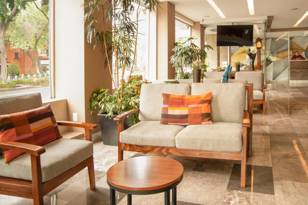 A lobby seating area beside tall windows and indoor plants.
