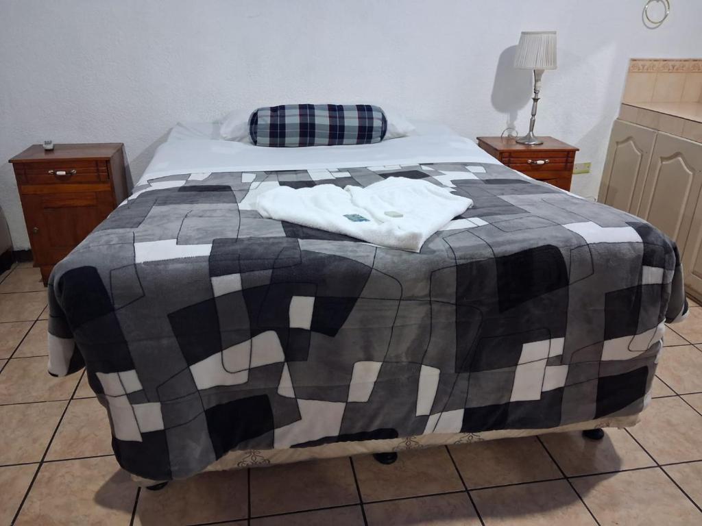 a bedroom with a bed with a black and white blanket at hotel kasa kamelot parque in Quetzaltenango