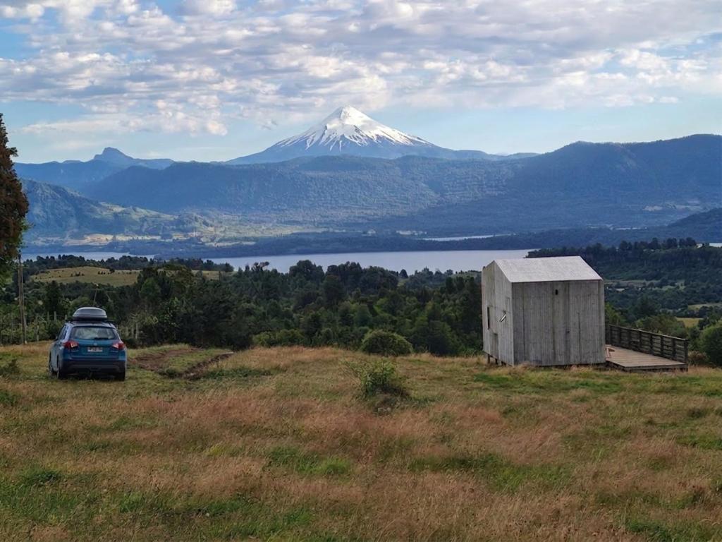 a car parked in a field with a snow covered mountain at Spectacular tiny house in an unforgettable setting in Ñilque
