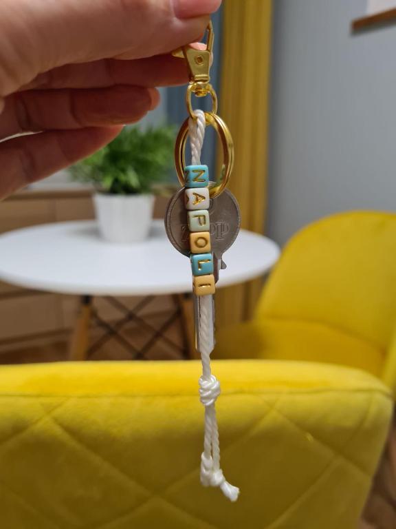 a hand holding a key to a yellow couch at Villa Bianca in Mikołajki