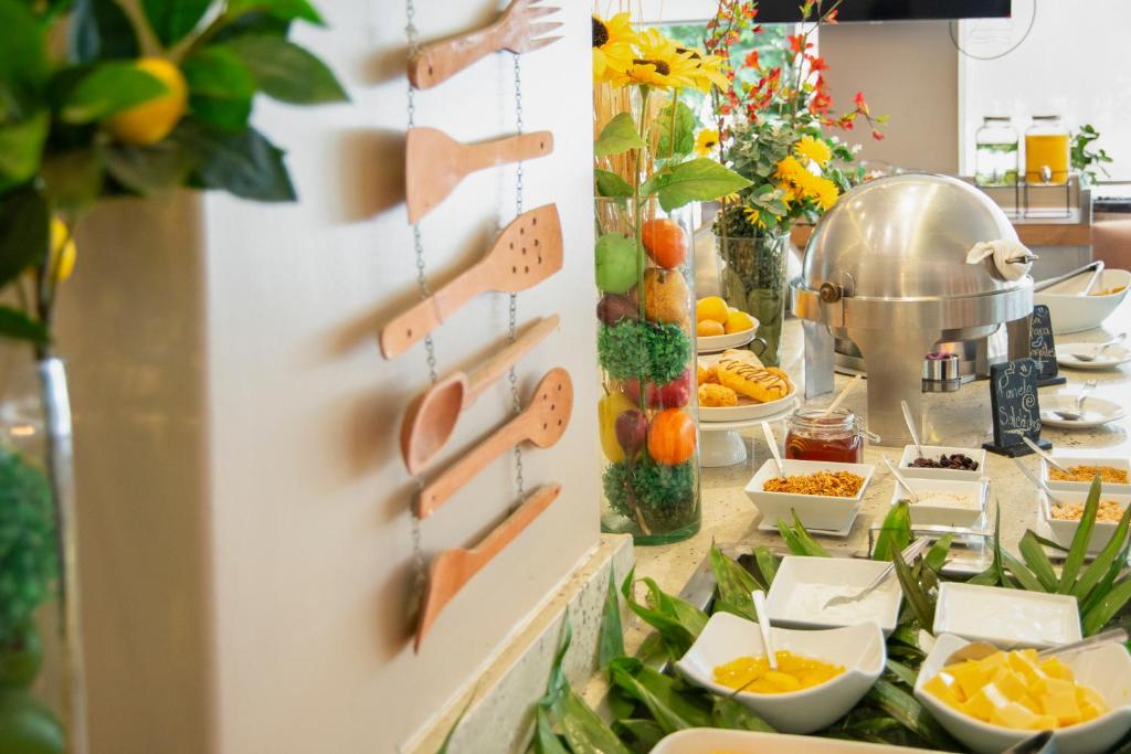 A decorated buffet counter with fruit, pastries, condiments and covered serving equipment.