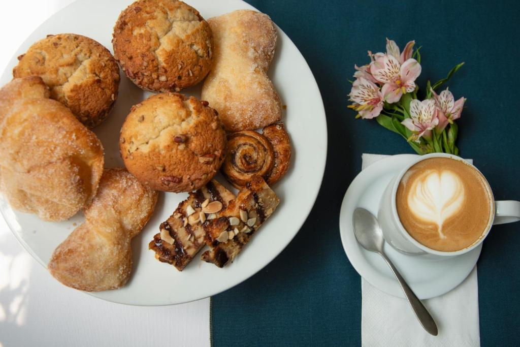 A pastry plate beside a cup of latte-style coffee and flowers.