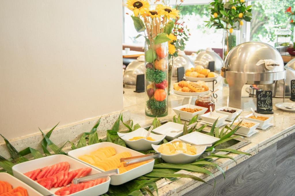 A breakfast buffet with cut fruit, pastries, condiments and covered hot dishes.