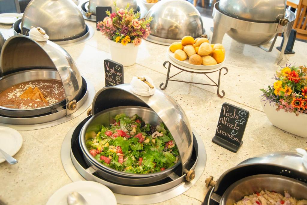 A buffet spread featuring salad, pasta, rice, sauces and small baked rolls.