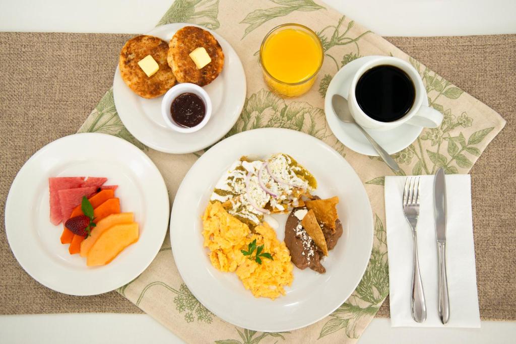 A plated breakfast with eggs, toast, fruit, juice and coffee.
