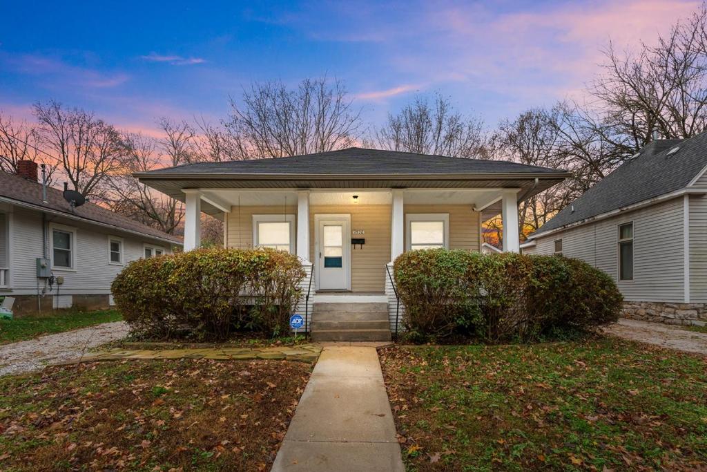 a white house with a porch and two bushes at Quiet 2BR Near Mercy Dog Friendly, Week & MO Rates in Springfield