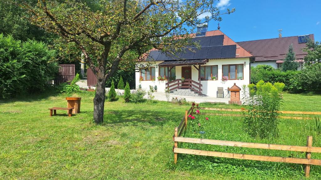 a house with a tree and two benches in the yard at La numărul 100, Nămăești in Nămăeşti