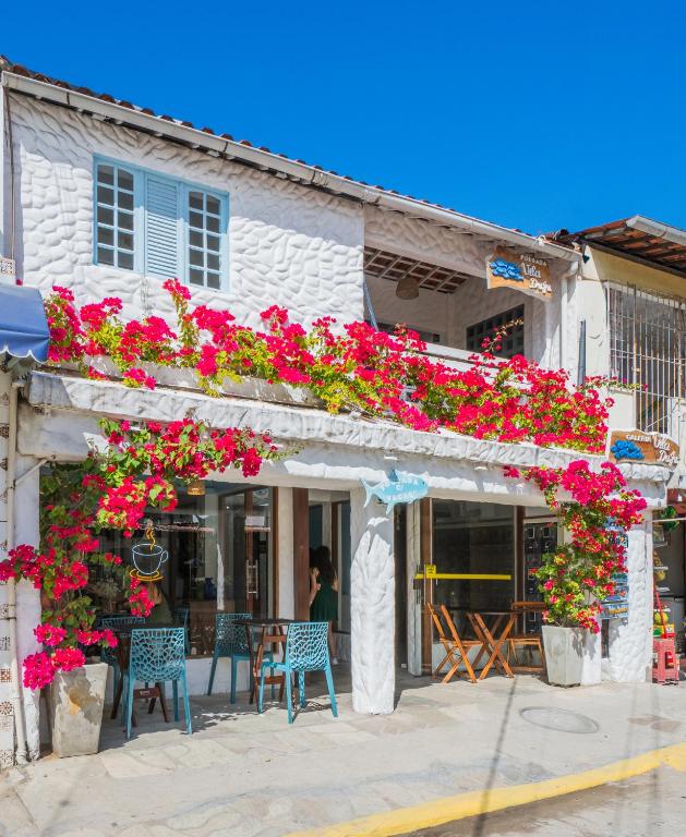 a building with pink flowers and blue chairs at Pousada Vila DuJu in Porto De Galinhas