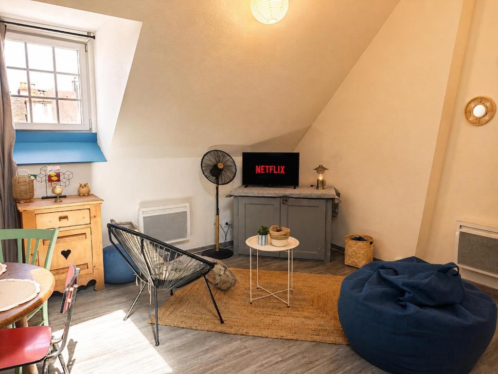 a attic room with a tv and a table and chairs at Le Nid Dolois in Dole
