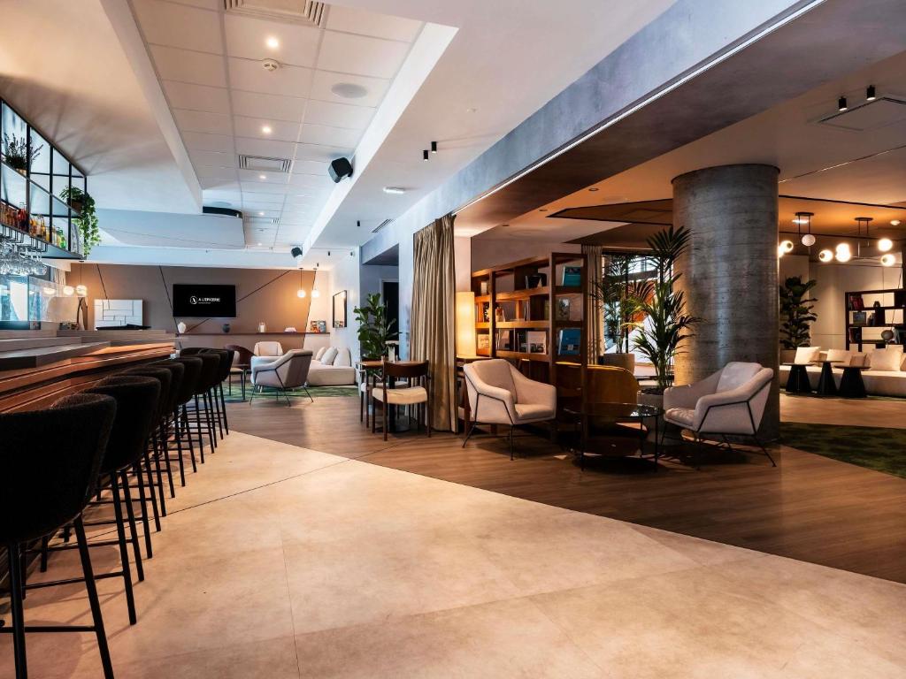 a bar in a hotel lobby with chairs and tables at Novotel Grenoble Centre in Grenoble