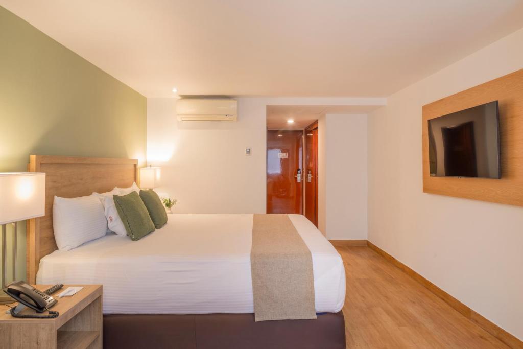 A bedroom with a large bed, television, air conditioning and entry area.