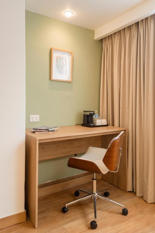 A built-in desk with a rolling chair and in-room coffee setup beside the curtains.
