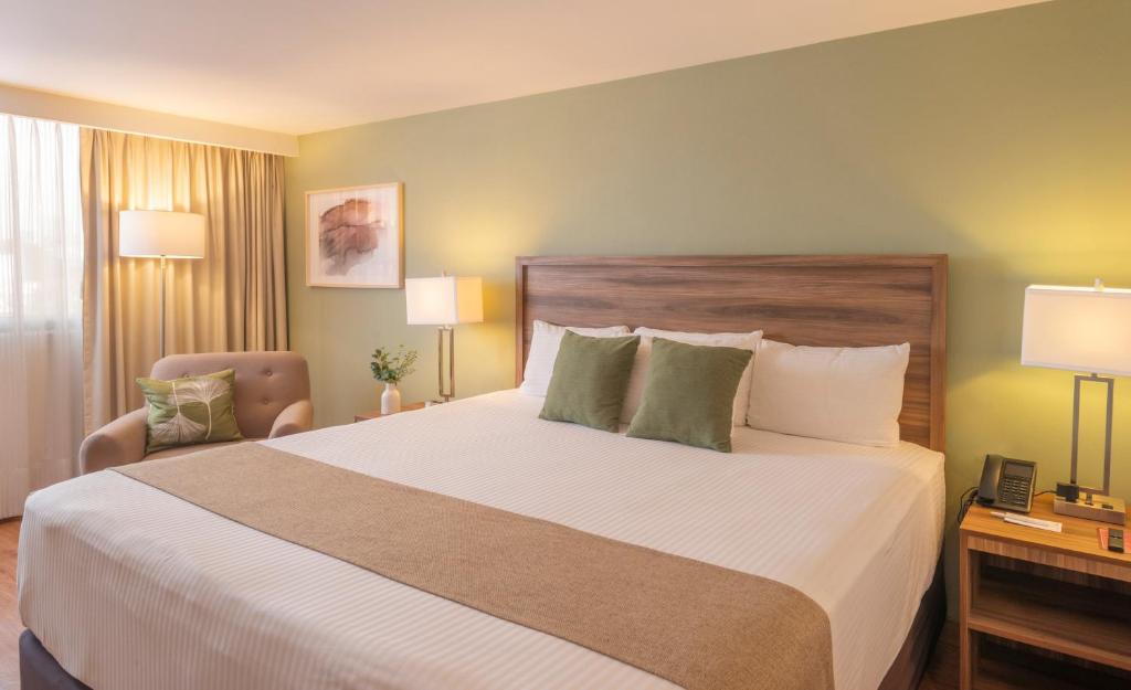 A large-bed bedroom with bedside lighting and a separate armchair near the window.