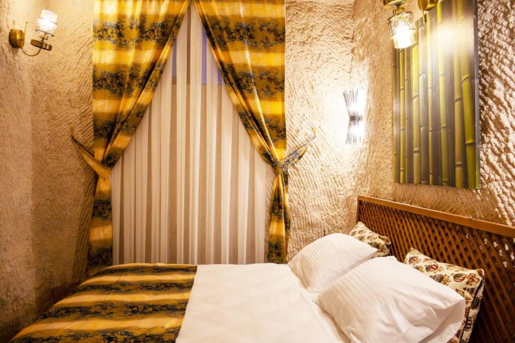 a bedroom with a bed and a window with curtains at ÖzkanHouse in Ürgüp