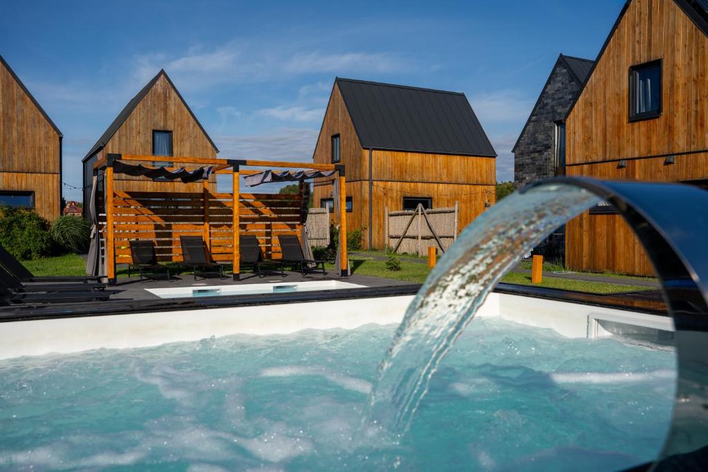 a pool with a water fountain in front of some barns at Letnisko Rusinowo in Jarosławiec
