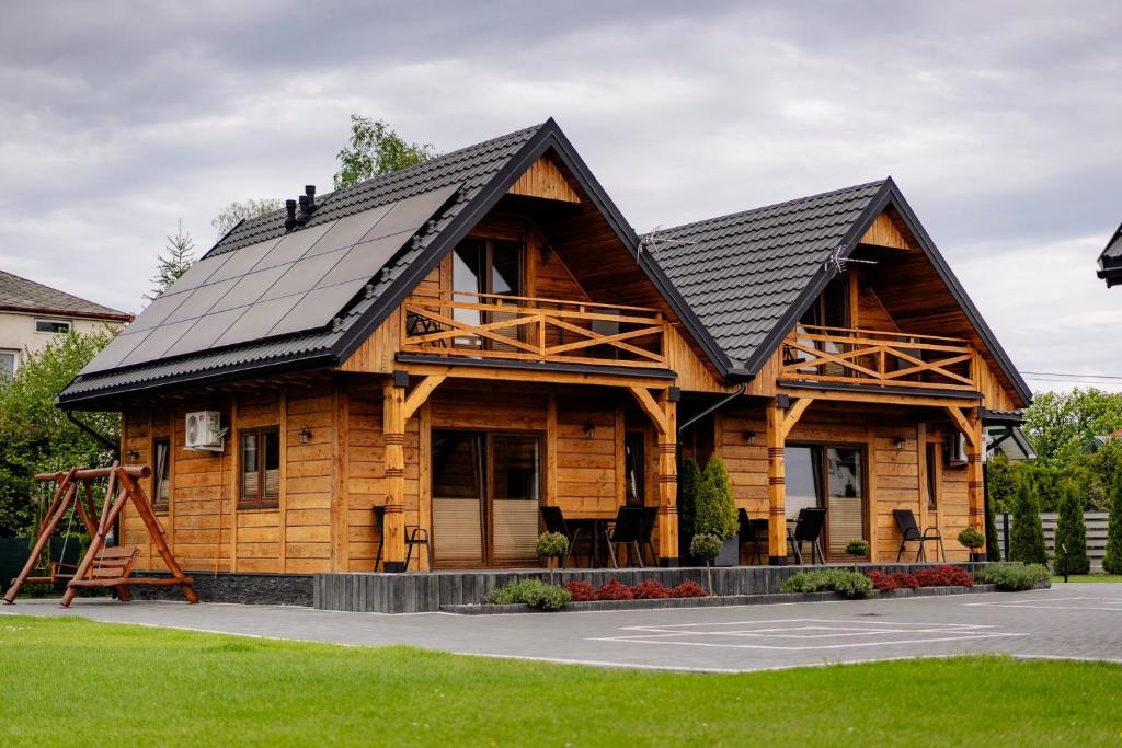 a log cabin with a black roof at Domki przy Alei in Krasnobród