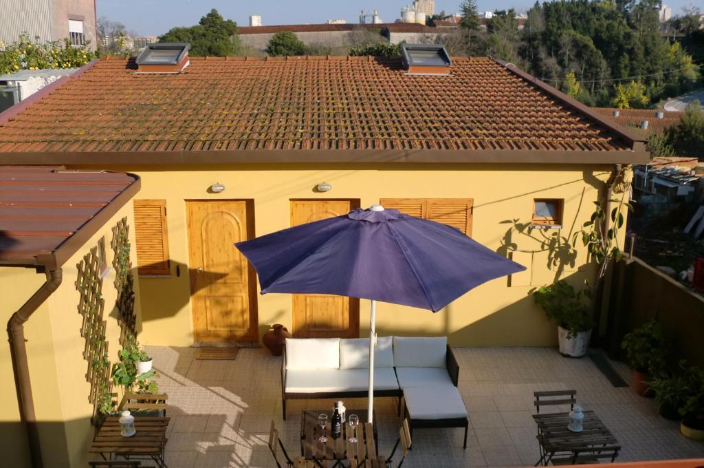 una casa y un patio con sombrilla y sillas en The Yellow House, en Vila Nova de Gaia