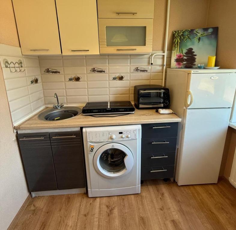 a small kitchen with a washing machine and a refrigerator at Omes puurs in Ventspils