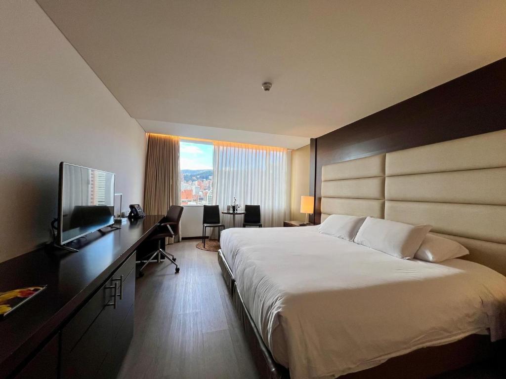 a hotel room with a large bed and a television at Hotel Estelar Milla De Oro in Medellín
