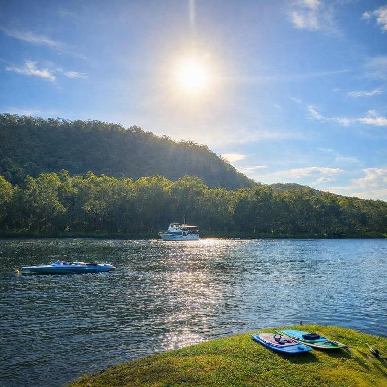 two boats on a lake with a boat in the distance at The River House - Wisemans Ferry in Wisemans Ferry