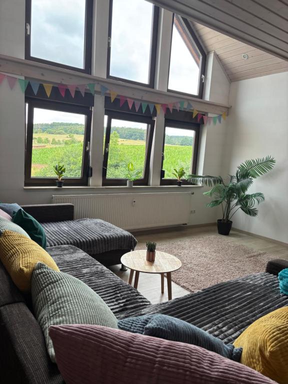a living room with couches and a table and windows at Ferienapartment Naturblick in Hausen