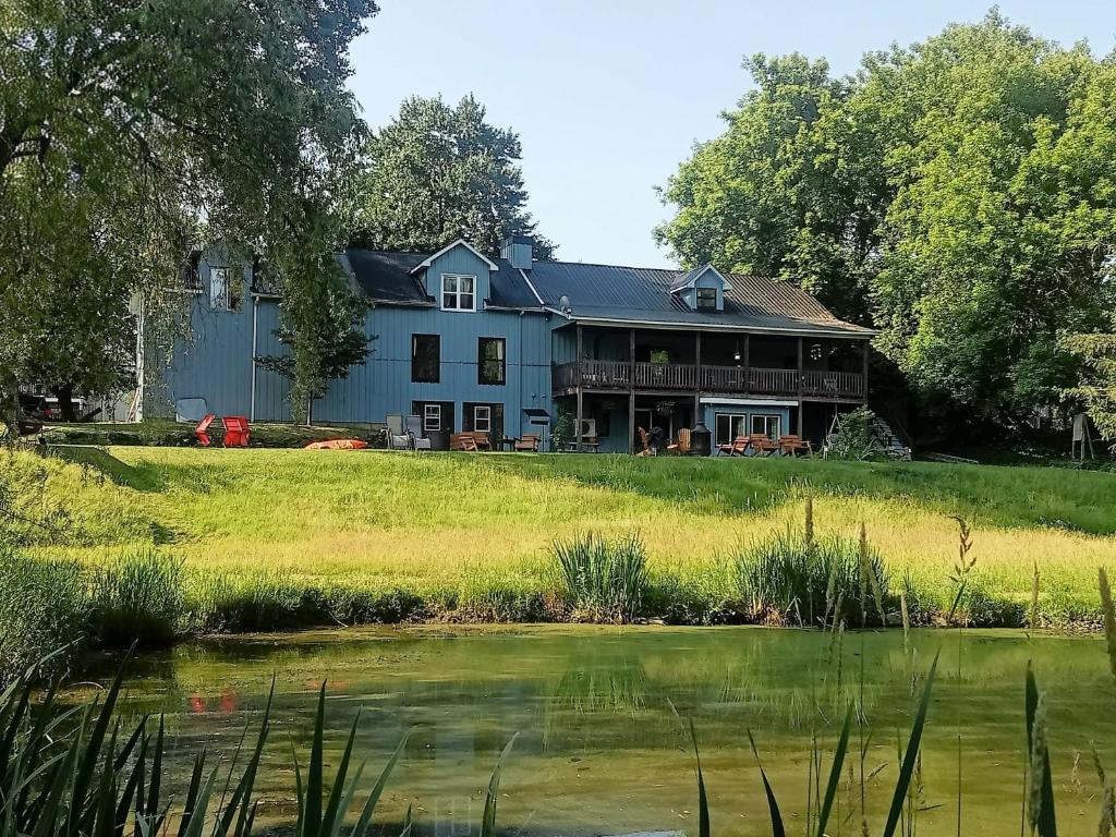 a large blue house with a pond in front of it at Slo-Brome gîte de charme slow life in Lac-Brome