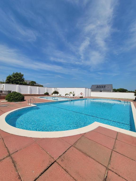 a large swimming pool on a brick patio at Cwtch y Môr - NEW Outdoor Pool Spacious 3 bed, sea & mountain views in Holy Island