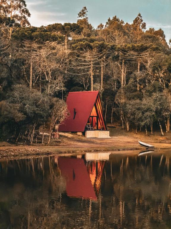 a red building next to a body of water at Oásis Pousada in Cambará