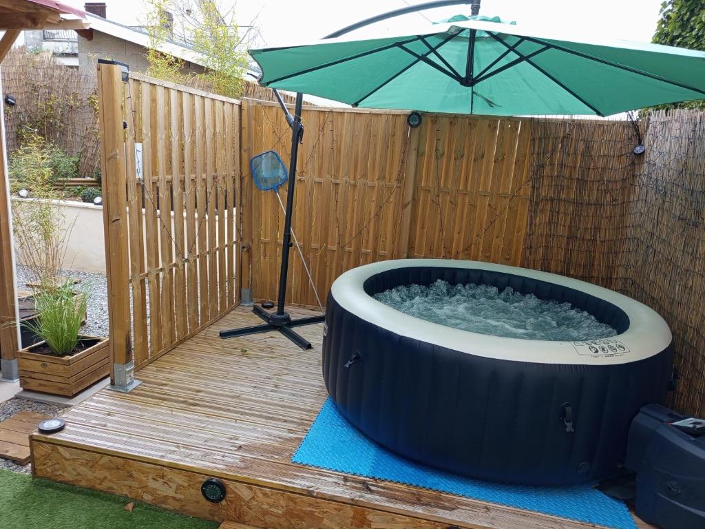 a hot tub with an umbrella on a wooden deck at Résidence des 4 saison in Cransac