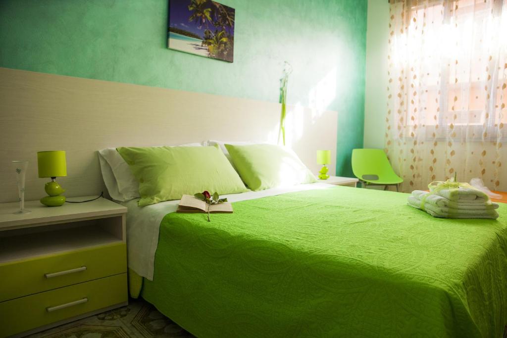 a green bedroom with a bed with a book on it at B&B Giosy in Portopalo