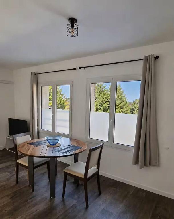 a dining room with a table and chairs and windows at Cosy appartement in Miniac-Morvan
