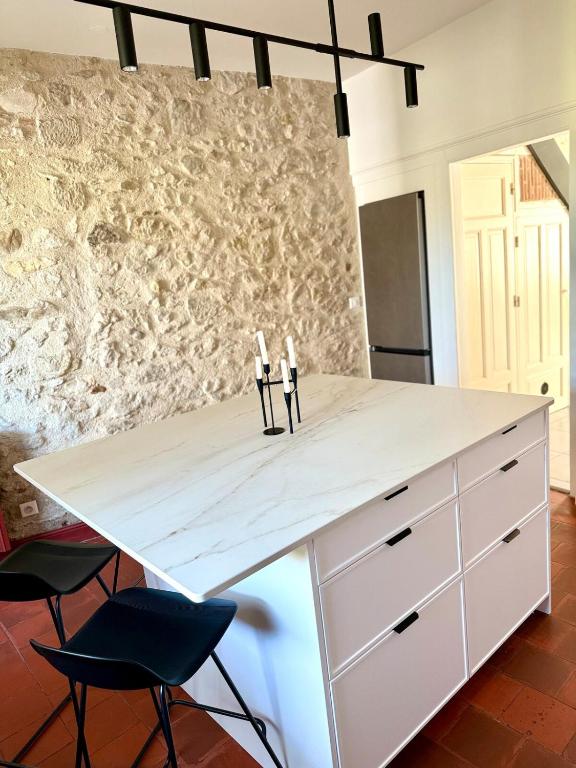 a kitchen with a white counter and two chairs at Maison Gazel in Castres