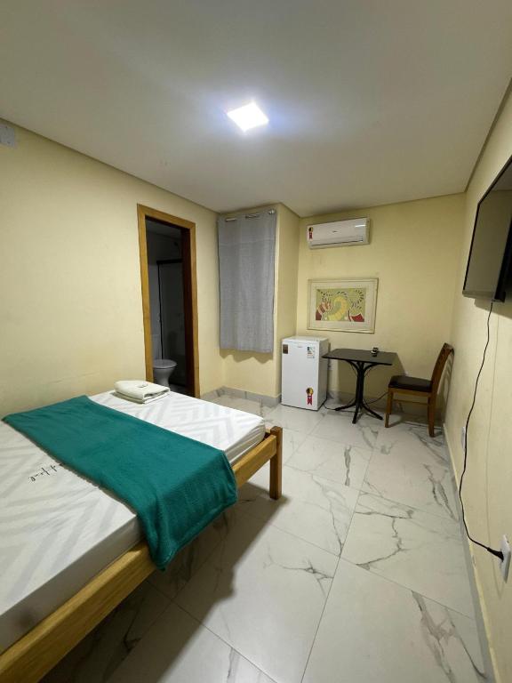a bedroom with a bed and a table and a television at Oeste Palace hotel in Brasília