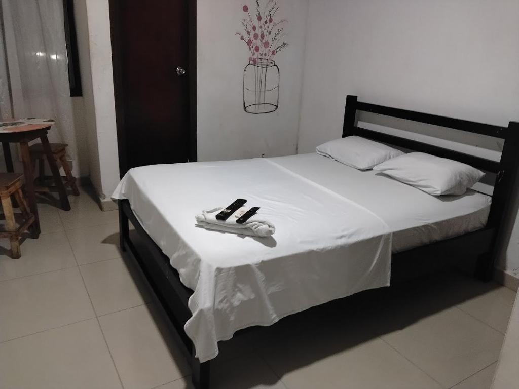 a bed with a white blanket and a pair of shoes on it at hotel habiby32 descansa in Barranquilla