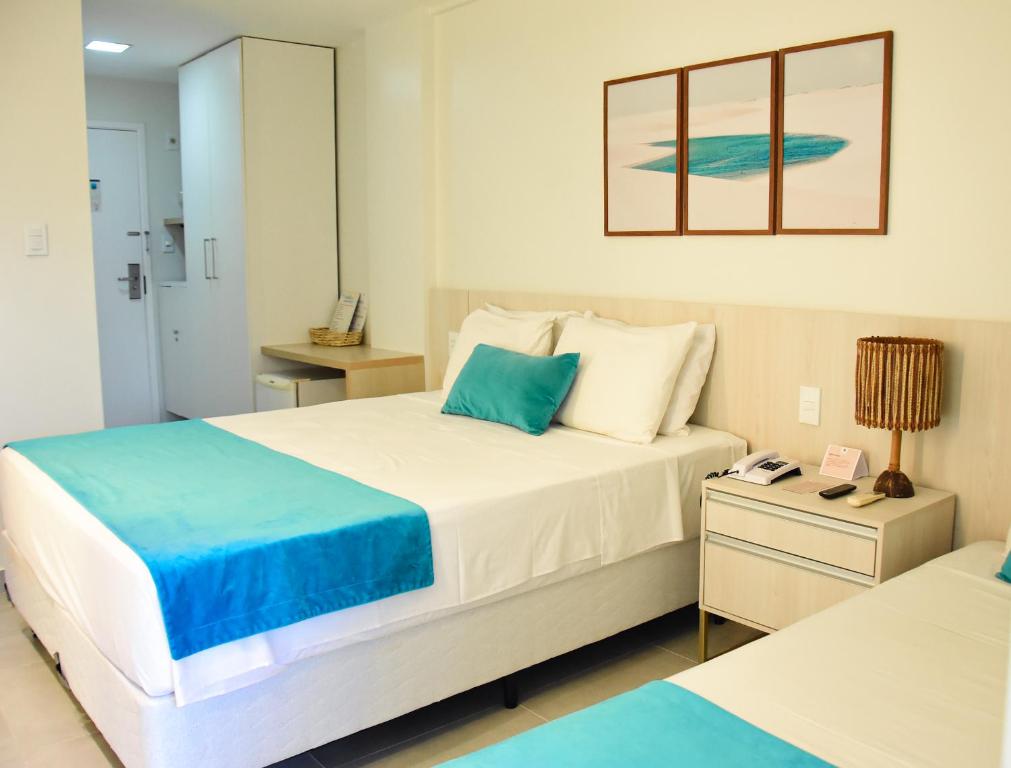 a bedroom with a large white bed and a night stand at Grand Lençóis Flat in Barreirinhas