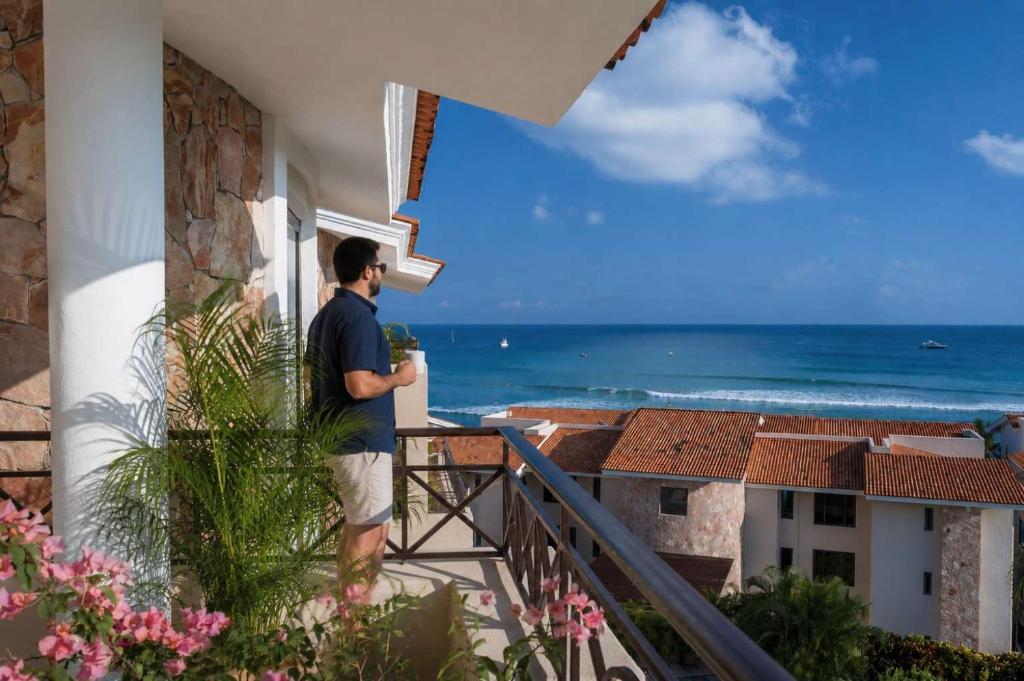 a man standing on a balcony looking out at the ocean at Luxury Oceanview Penthouse in HDM in Punta Mita
