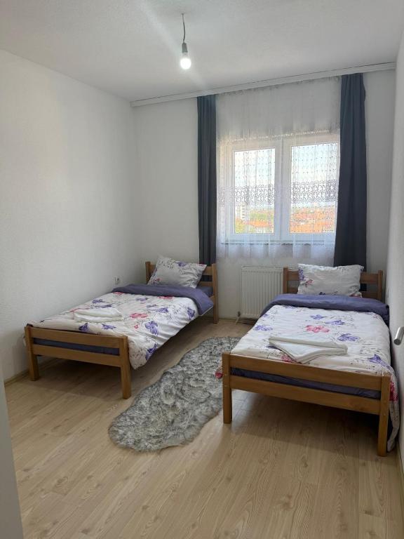 a bedroom with two beds and a rug at Unik Apartment in Kosovo Polje