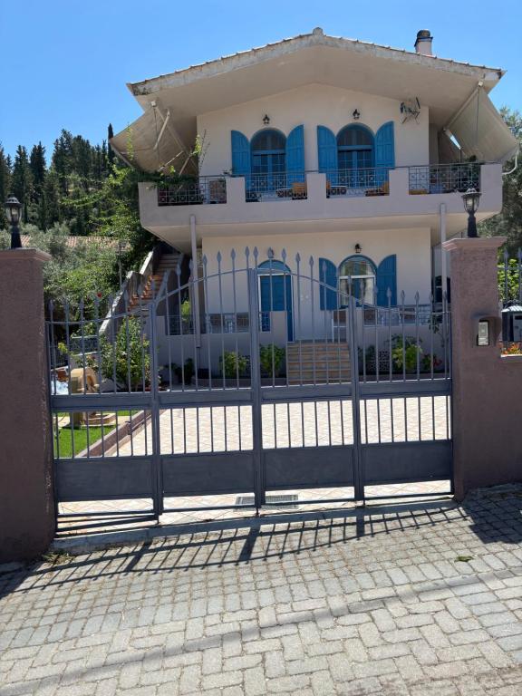 a gate in front of a house with blue doors at Myrovolos Guesthouse in Apolpaina