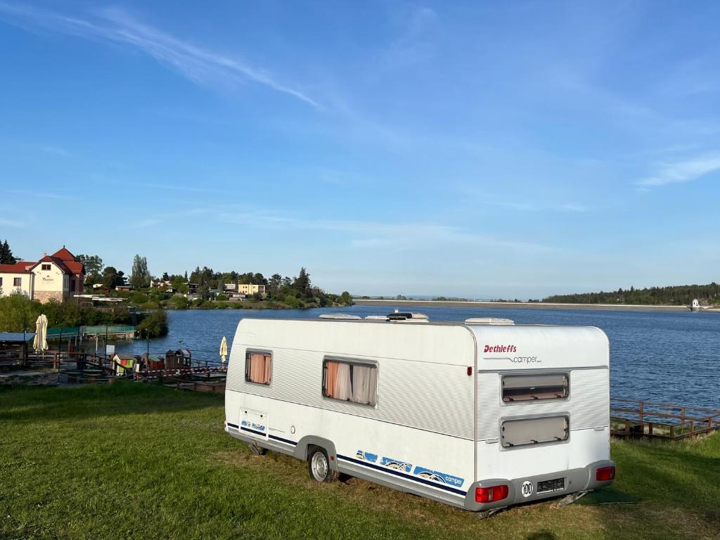 a white caravan parked next to a body of water at Karavan u přehrady in Prostějov