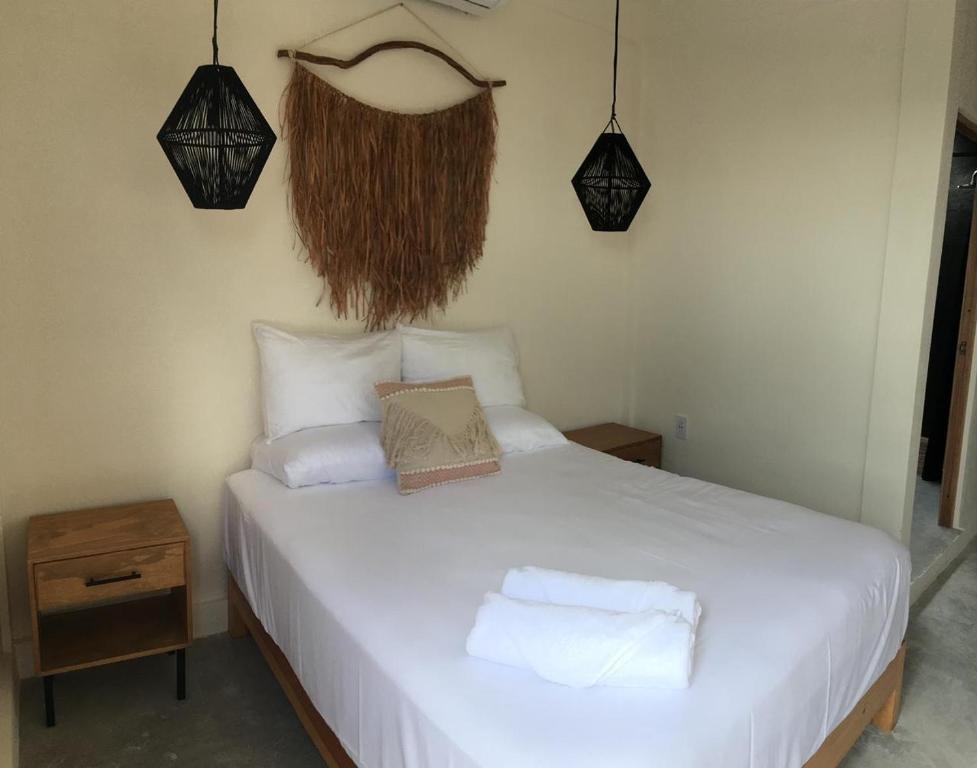a bedroom with a white bed with two pillows at Black flamingo in Holbox Island
